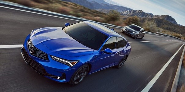 Two 2023 Integra in Apex Blue Pearl and Liquid Carbon Metallic driving in a highway Two 2023 Integra in Apex Blue Pearl and Liquid Carbon Metallic driving in a highway