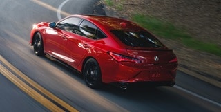 2026 Acura Integra A-Spec with Technology in Performance Red Pearl driving up road. 2026 Acura Integra A-Spec with Technology in Performance Red Pearl driving up road.