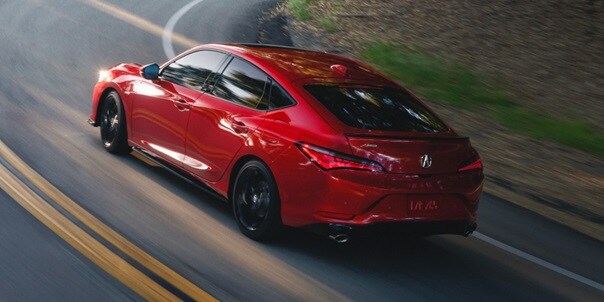 2026 Acura Integra A-Spec with Technology in Performance Red Pearl driving up road. 2026 Acura Integra A-Spec with Technology in Performance Red Pearl driving up road.