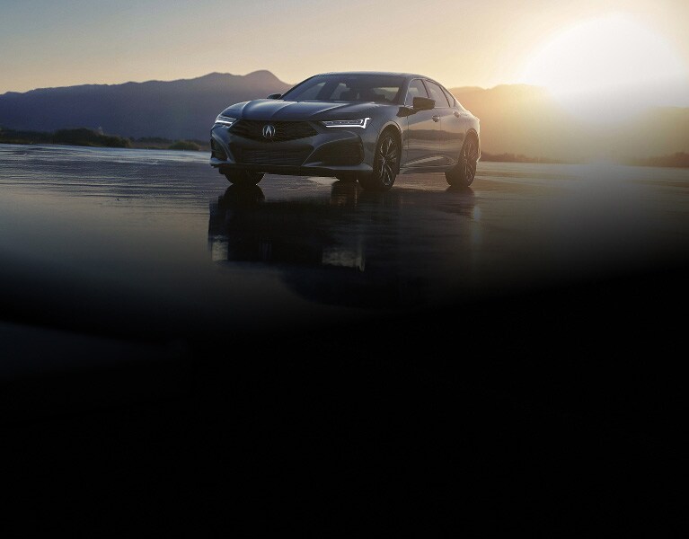 2026 Acura TLX with Technology Package in Liquid Carbon Metallic, front three-quarter view at sunset with mountains (Premium Sport Sedan).