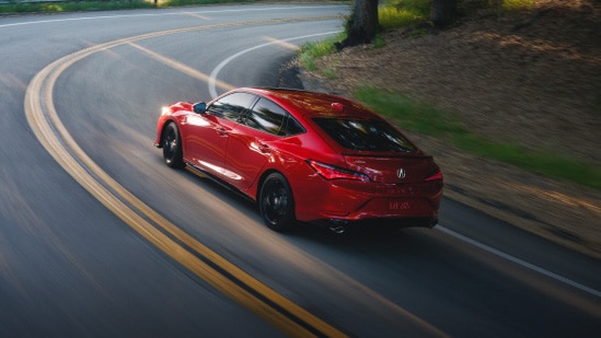 2026 Acura Integra A-Spec with Technology Package in Performance Red Pearl back driving on a winding road (Premium Sport Compact).