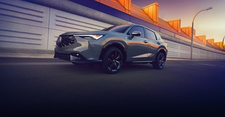 2026 Acura ADX A-Spec in Urban Gray Pearl profile parked in front of a modern urban building (Premium Compact SUV).
