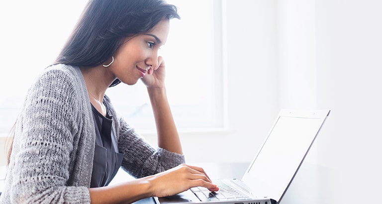 Woman looking at laptop by a window